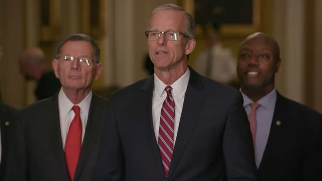 Senator John Thune standing with two men behind him