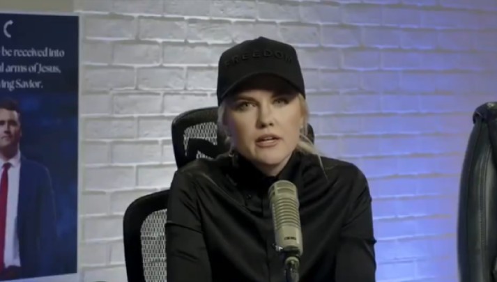 Erika Kirk sitting in chair wearing a black hat