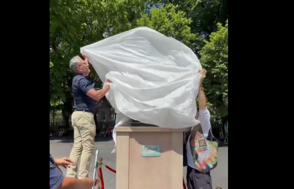 A covered statue with the cover being removed