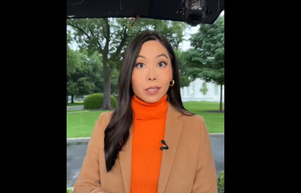 Woman wearing an orange sweater with tan jacket